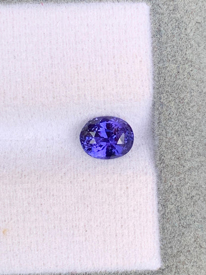Le Saphir violet • 1,10ct de [NOUVEAU] Bonnot Paris, une exquise gemme ovale du Sri Lanka, repose sur une surface texturée grise et blanche, reflétant la lumière pour révéler ses facettes étonnantes et son allure intemporelle.