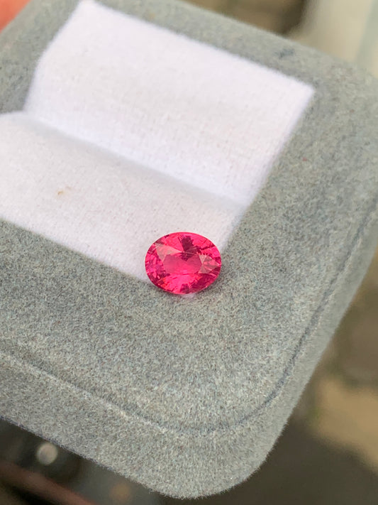 La pierre précieuse Spinelle Mahenge • 1,55ct de Bonnot Paris, dans une teinte rose ronde et vibrante, est élégamment présentée sur un coussin blanc dans un écrin à bijoux gris.