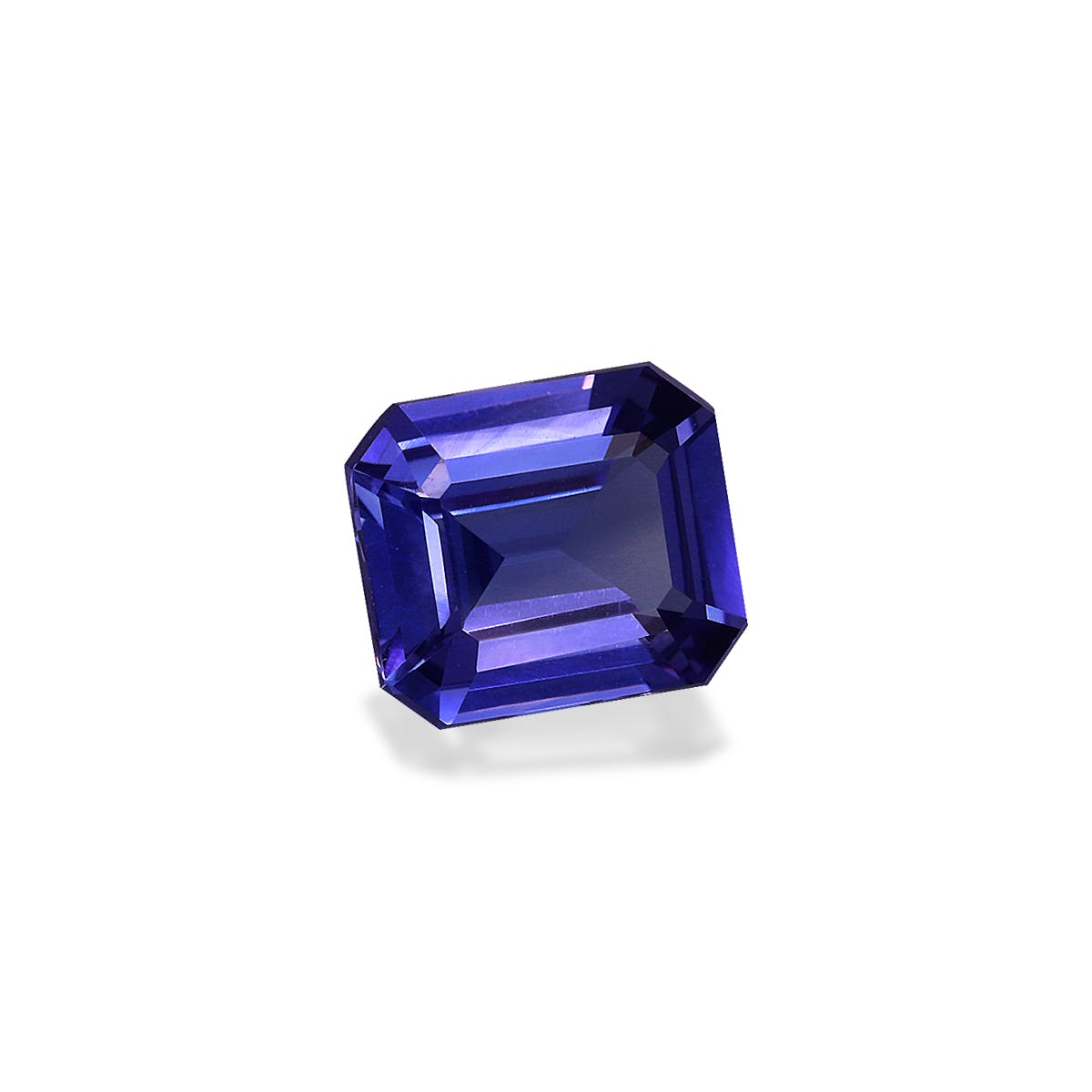 Une tanzanite taille émeraude de 2,6 carats de Bonnot Paris, aux facettes acérées et à la teinte bleu profond, est présentée sur un fond blanc uni, projetant une ombre subtile.