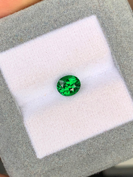 Une Tsavorite vibrante de 1,53 ct de [NOUVEAU] Bonnot Paris est présentée sur un fond coussiné blanc avec une bordure grise, ses facettes captant la lumière pour mettre en valeur sa clarté et sa couleur.