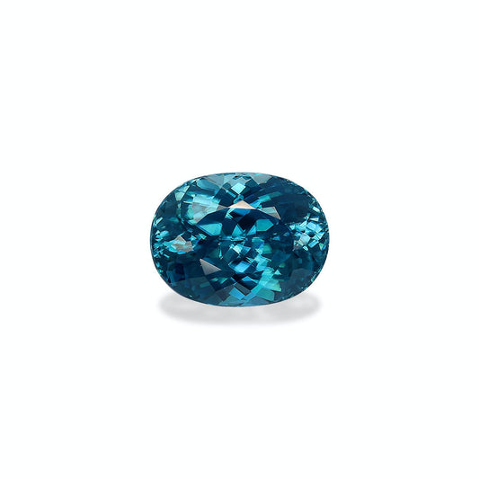 Le Zircon Bleu · 6,12 ct de Bonnot Paris est une exquise pierre précieuse bleue étincelante de taille ovale sertie sur un fond blanc, mettant en valeur ses facettes complexes et sa teinte turquoise profonde.